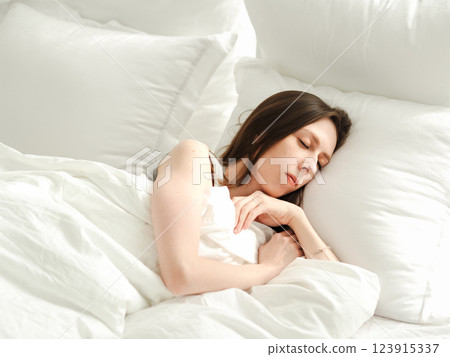 young woman sleeping on bed with white linen and air pillows. Correct regime and good sleep for female cycle young woman sleeping on bed with white linen and air pillows. Correct regime and good sleep for female cycle 123915337