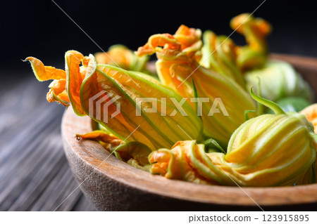 Macro shot of fresh zucchini flowers in wooden plate Macro shot of fresh zucchini flowers in wooden plate 123915895