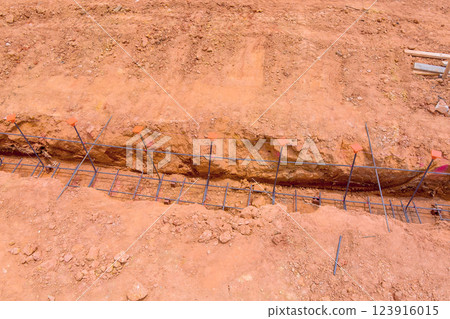 Foundation trench for building is being prepared, showcasing rebar tied together in ground at construction site. 123916015