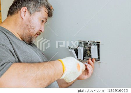 An electrician repairs home switches during house renovation 123916053