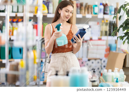 Young woman chooses cleaning spray in store 123916449