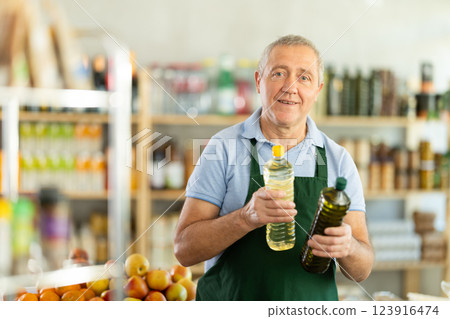 Mature salesman is offering vegetable oil in grocery store Mature salesman is offering vegetable oil in grocery store 123916474