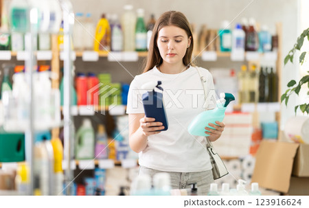 Young woman chooses cleaning spray in store 123916624