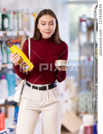 Young woman chooses floor and wood cleaner in store 123916639