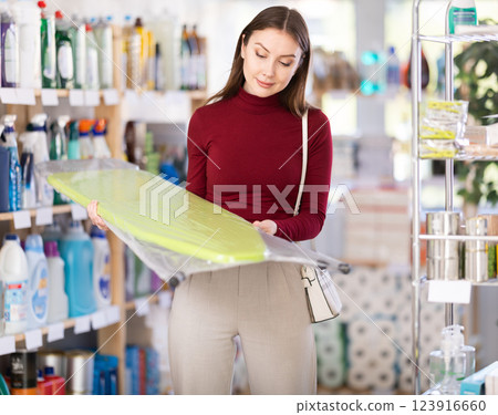 Young woman chooses ironing board in store 123916660