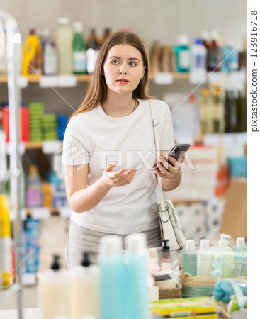 Girl looks at phone screen, scrolling through screen shopping list and remembers desired product Girl looks at phone screen, scrolling through screen shopping list and remembers desired product 123916718