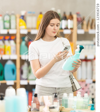 Girl buyer scans qr code on tile cleaner spray label Girl buyer scans qr code on tile cleaner spray label 123916719