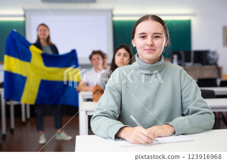 Female teacher tells her classmates about the country of Sweden, holding flag in her hands 123916968
