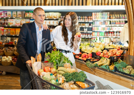 Positive young couple in the supermarket, took fresh apples on the counter Positive young couple in the supermarket, took fresh apples on the counter 123916970