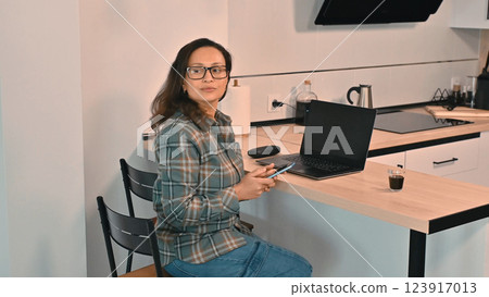 Woman Working Remotely in a Modern Home Kitchen Setting 123917013