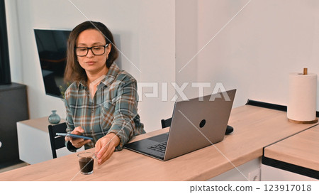 Businesswoman Working Remotely at Home Office with Laptop and Coffee 123917018