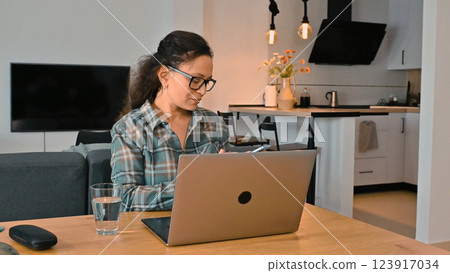 Woman Working Remotely on Laptop in Contemporary Home Setting 123917034