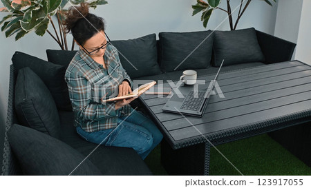Woman Working Remotely at an Outdoor Workspace with Laptop and Notebook 123917055