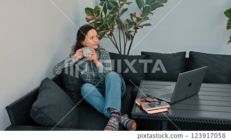 Woman Relaxing with Coffee While Working Remotely from a Cozy Outdoor Space Woman Relaxing with Coffee While Working Remotely from a Cozy Outdoor Space 123917058