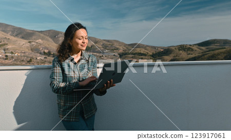 Woman Using a Laptop Outdoors with Scenic Mountain View Woman Using a Laptop Outdoors with Scenic Mountain View 123917061