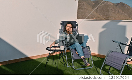 Relaxed Freelancer Working Remotely on a Terrace with Scenic Mountain View Relaxed Freelancer Working Remotely on a Terrace with Scenic Mountain View 123917064