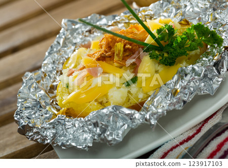 Tasty cooked baked in foil potatoes with bacon, cheese and fried onion Tasty cooked baked in foil potatoes with bacon, cheese and fried onion 123917103