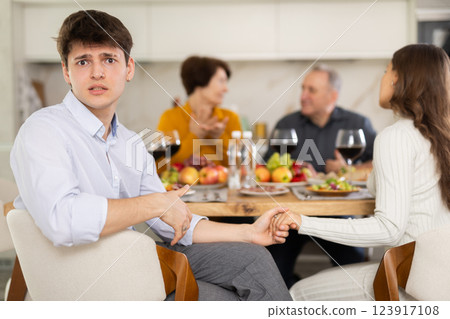 Upset young guy at family holiday table with parents. Unpleasant discussion Upset young guy at family holiday table with parents. Unpleasant discussion 123917108