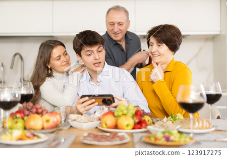 Happy family members looking through photos in home interior during family holiday 123917275