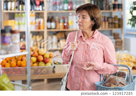 Portrait of female shopper choosing variety of products in grocery hypermarket 123917285
