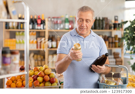 Mature man is choosing beer in grocery store Mature man is choosing beer in grocery store 123917300