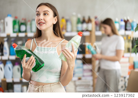 Young woman chooses dishwashing detergent in store Young woman chooses dishwashing detergent in store 123917302