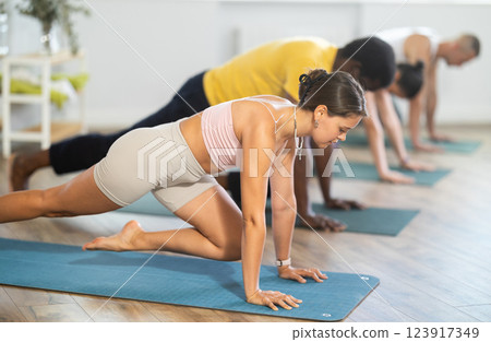 Young woman coach and students perform greeting to sun during training in studio 123917349