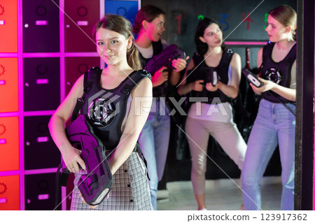 Cheerful and happy girl pose in locker room before laser tag match. Cheerful and happy girl pose in locker room before laser tag match. 123917362