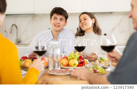Cheerful young couple having dinner with elderly parents Cheerful young couple having dinner with elderly parents 123917390