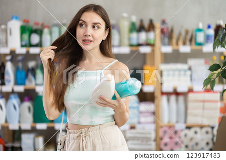 Woman looking for trademark sign on label, chooses eco friendly shampoo or shower gel 123917483