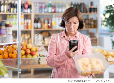Female purchaser scanning QR code or barcode of chicken thighs in shop 123917539