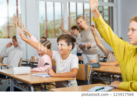 School pupils raise their hands up in classroom School pupils raise their hands up in classroom 123917566