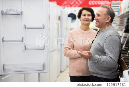 Middle aged wife and husband picking new refrigerator in store 123917581