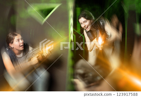 Girls play laser tag, jokingly fight with light weapons Girls play laser tag, jokingly fight with light weapons 123917588