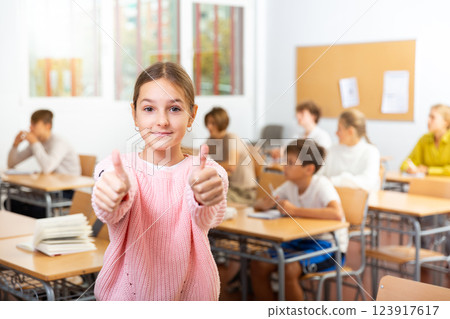 Smiling schoolgirl hold thumbs up Smiling schoolgirl hold thumbs up 123917617