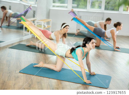 Group of young women doing pilates with band Group of young women doing pilates with band 123917655