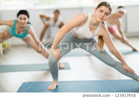 Group of young women doing stretching in studio Group of young women doing stretching in studio 123917658