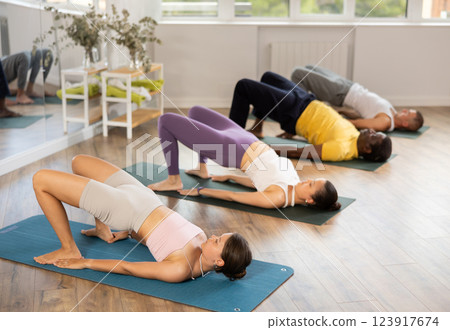 Young woman performing Setu Bandha Sarvangasana in yoga class 123917674