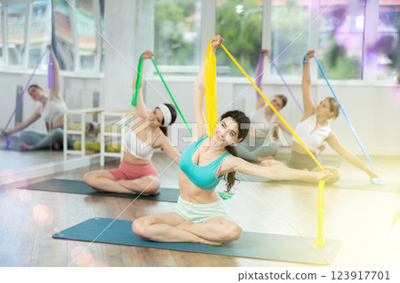 Group of women doing exercises with resistance bends in fitness room Group of women doing exercises with resistance bends in fitness room 123917701