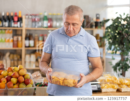 Senior man holding plastic containers with poultry half chicken carcass, choose chicken meat. 123917737