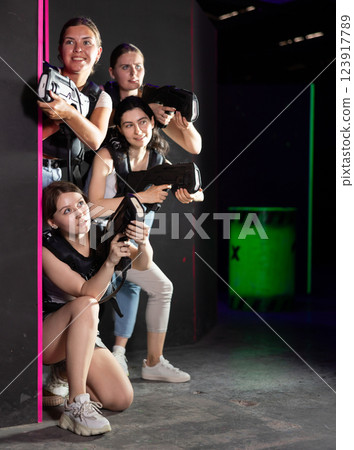 Smiling girlfriends playing laser tag game with colored laser Smiling girlfriends playing laser tag game with colored laser 123917789