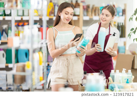 saleswoman offers the customer shampoo options, and the woman scans the barcode saleswoman offers the customer shampoo options, and the woman scans the barcode 123917821