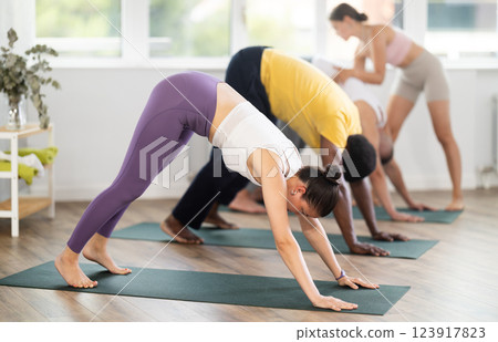 Woman doing downward facing dog pose in group yoga studio Woman doing downward facing dog pose in group yoga studio 123917823