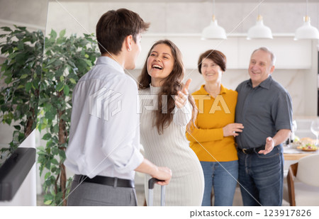 Cheerful guy returning home or coming to visit to parents. Happy family greeting at door 123917826