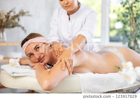 Young woman relaxing in spa center during back and shoulders massage 123917829