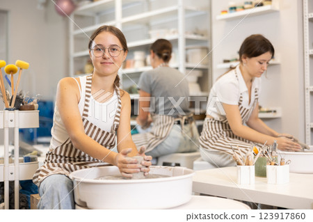 Woman teacher and students make products on potter's wheel 123917860