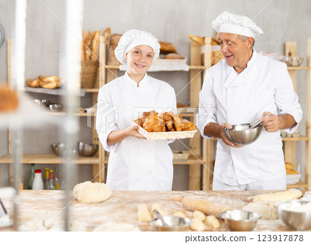 Grandfather approving granddaughter freshly baked croissants in family bakery 123917878