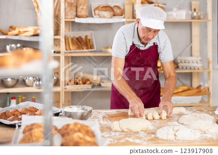Elderly man baker molding pieces of dough 123917908