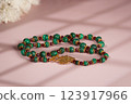 Malachite necklace photographed on a pink background 123917966