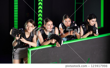Cheerful girlfriends with laser pistols gaming together in laser tag labyrinth Cheerful girlfriends with laser pistols gaming together in laser tag labyrinth 123917998